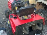 an image of a red and black lawn mower parked in a parking lot