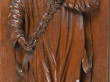a close up of a wooden plaque with a statue of a man holding a cross