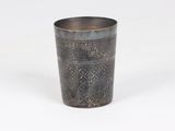an old metal cup with a design on the rim