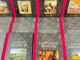 six books on a table with a red ribbon and a picture of a man in a suit
