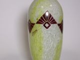 un vase vert orné d'un motif sur un fond blanc