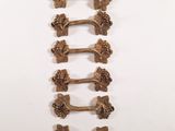 six brass handles with grapes on them on a white surface