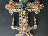 une vieille croix en argent ornée de pierres colorées, posée sur un fond noir