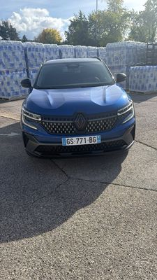 une voiture bleue garée sur un parking, à côté d'une pile de cartons