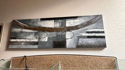 une horloge accrochée au mur au-dessus d'un lit, avec un tableau accroché au mur