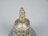 a silver bell with a gold decoration on it