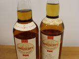two bottles of whisky sitting on top of a wooden table