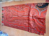 a large red and orange scarf hanging on a wall