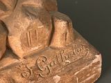 statue of a man sitting on top of a rock with a clock on it ' s face