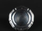 a silver plate on a stand against a black background