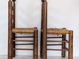 two wooden chairs and a small stool in front of a white wall