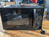 a black microwave sitting on a wooden table in a warehouse