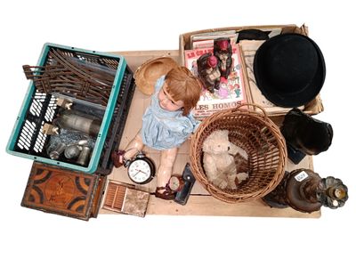 a doll sitting on the floor next to a pile of items