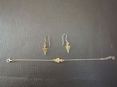 deux paires de boucles d'oreilles et un bracelet posés sur un fond noir