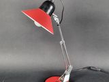 une lampe de bureau noire et rouge posée sur une surface noire