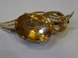 a close up of a brooch with a golden stone on it