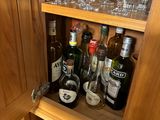 a wooden cabinet with wine glasses and bottles on it