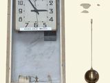 a clock that is hanging on the wall next to a pendulum