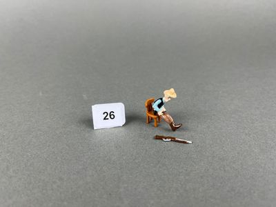 une figurine représentant un homme assis sur une chaise à côté d'un panneau
