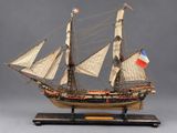 une vieille maquette en bois représentant un voilier arborant un drapeau