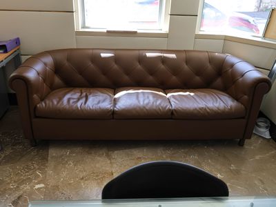 a brown leather couch sitting in front of a window