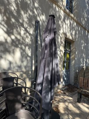des tables et des chaises à l'extérieur d'un bâtiment, avec un parasol, par une journée ensoleillée