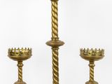 three brass candlesticks with crowns on them on a white surface