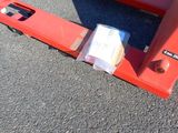 a red fork lifter sitting in the middle of a parking lot