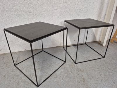 une paire de tables d'appoint en métal noir posées sur un sol en béton
