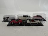 five toy cars in a display case on a white surface