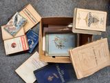 une boîte remplie de livres posée par terre, à côté d'autres livres