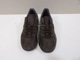brown sued sneakers with laces on top of them on a white surface