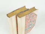 two books are stacked on top of each other on a white surface