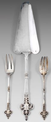 une cuillère et une fourchette en argent, ainsi qu'un repose-cuillère, posés sur une table