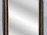 a black and gold framed mirror on a white wall