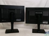 two black computer monitors sitting side by side on a white surface