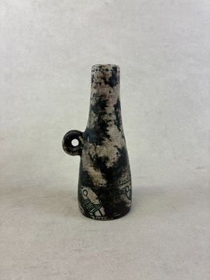 un vase noir et blanc posé sur une surface blanche