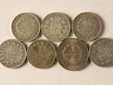 six pièces de monnaie britanniques différentes empilées les unes sur les autres sur une surface blanche