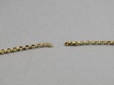 a close up of two gold chains on a gray surface