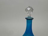 a blue glass bottle with a crystal stopper on it