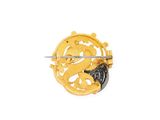 a yellow and black brooch on a white background