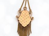 a close up of a gold necklace with fringes on a white background