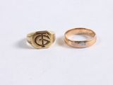 two gold rings with initials on them sitting on a white surface