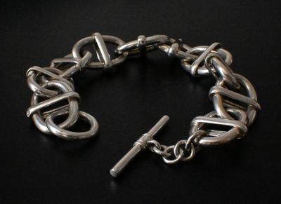 a silver bracelet with a cross on it on a black surface
