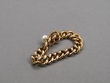 a close up of a gold chain bracelet with a pearl bead