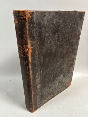 an old book sitting on top of a white table next to a clock