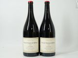 two bottles of red wine sitting on top of a white table