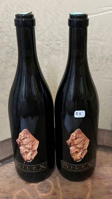 deux bouteilles de vin posées sur un tonneau en bois