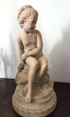 une petite statue représentant un garçon assis sur un rocher