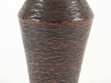 un vase brun posé sur une surface blanche